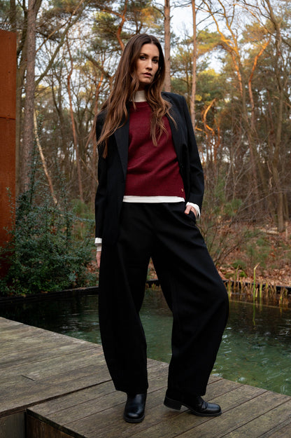 zwarte barrel pantalon met een rode trui en zwarte blazer erboven