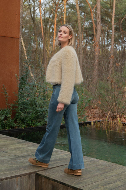 zijaanzicht model die de porto jeans met stone bleached wassing draagt en daarboven een fluffy jasje