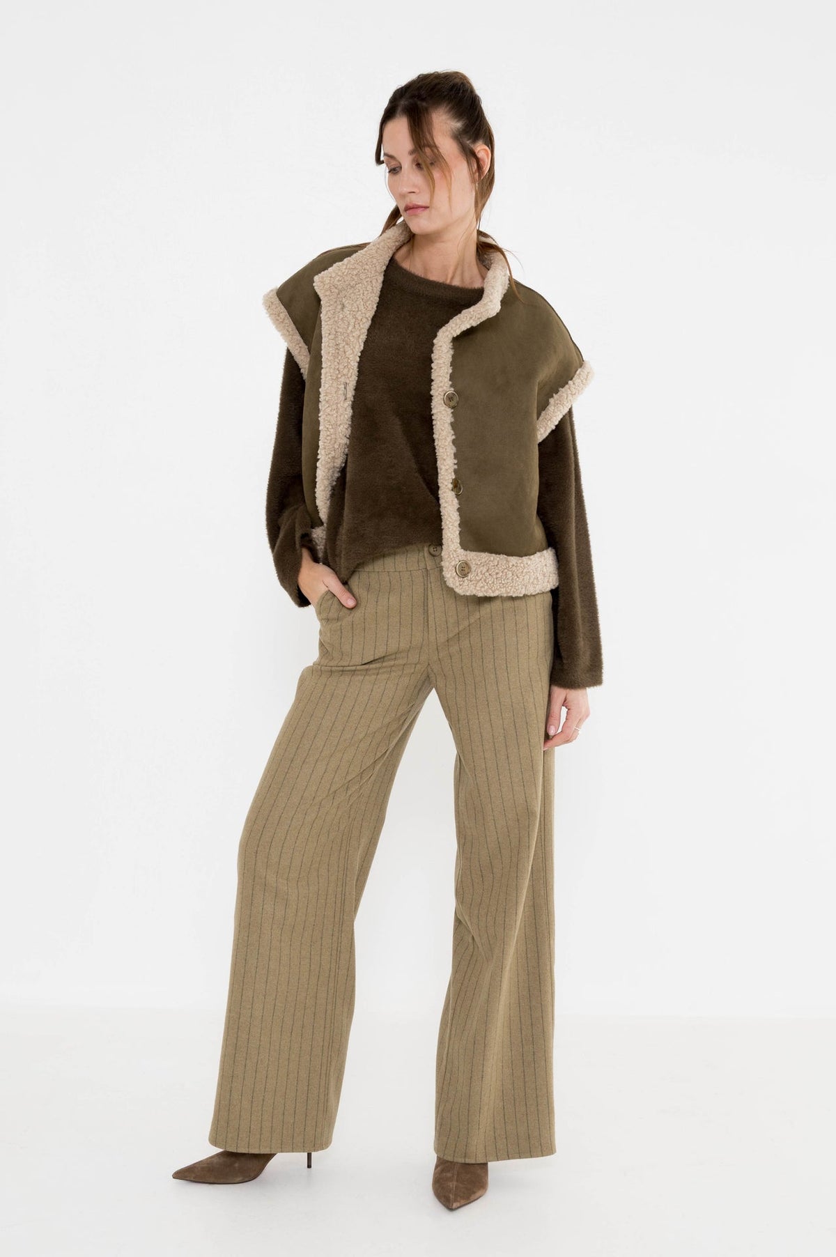 complete damesoutfit voor de herfst met khaki gestreepte broek, mosgroene damestrui en teddy gilet met korte mouwen en knoopsluiting
