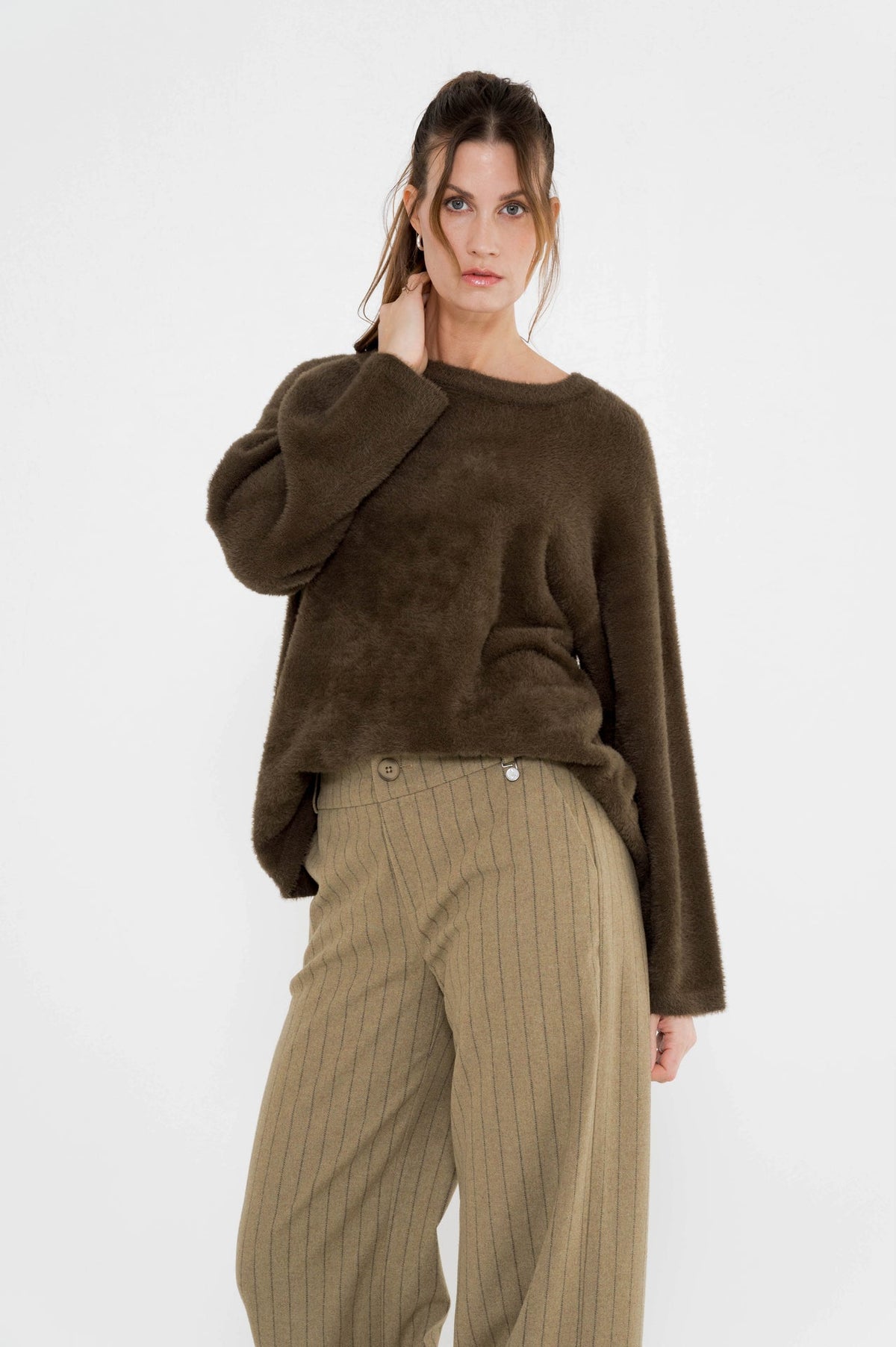 dame draagt de sella khaki gestreepte broek met daarboven een mosgroene trui