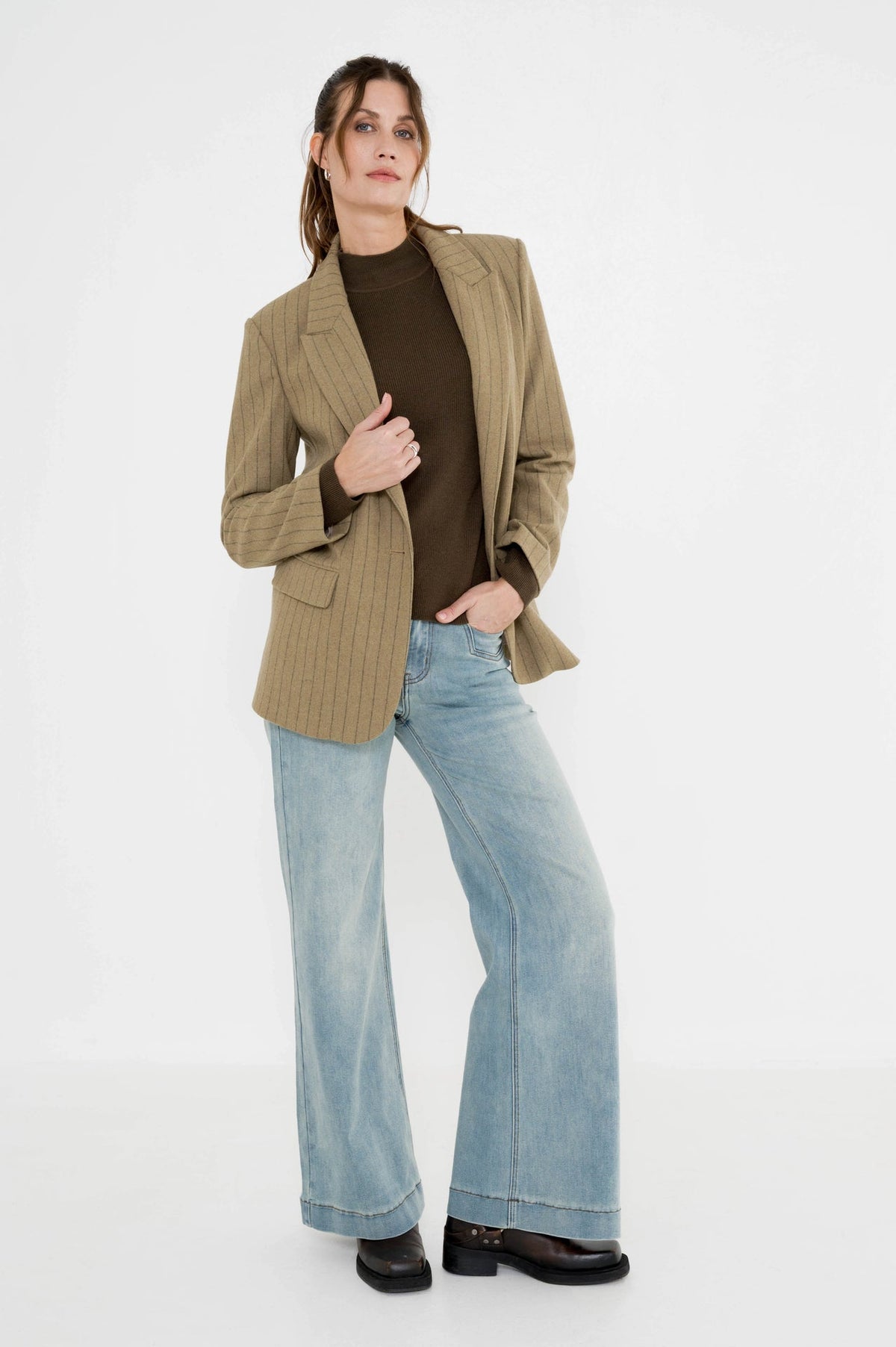 lichte jeans met wijde pijpen en daarboven een khaki blazer met een mosgroene coltrui
