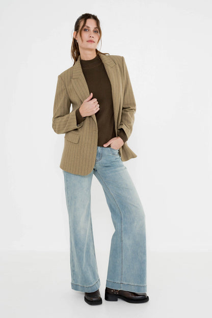 lichte jeans met wijde pijpen en daarboven een khaki blazer met een mosgroene coltrui