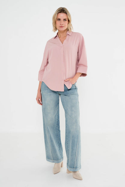model draagt palazzo jeans met een lichte wassing gecombineerd met een roze zachte blouse 