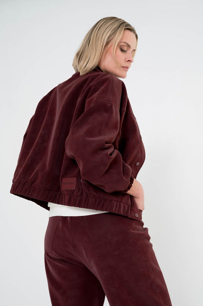 model showt achterkant van wijnrode broek brooke met een passend jasje erboven als complete set