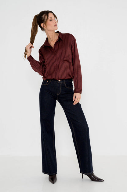 dame draagt donkere denim wide leg met wijnrode blouse