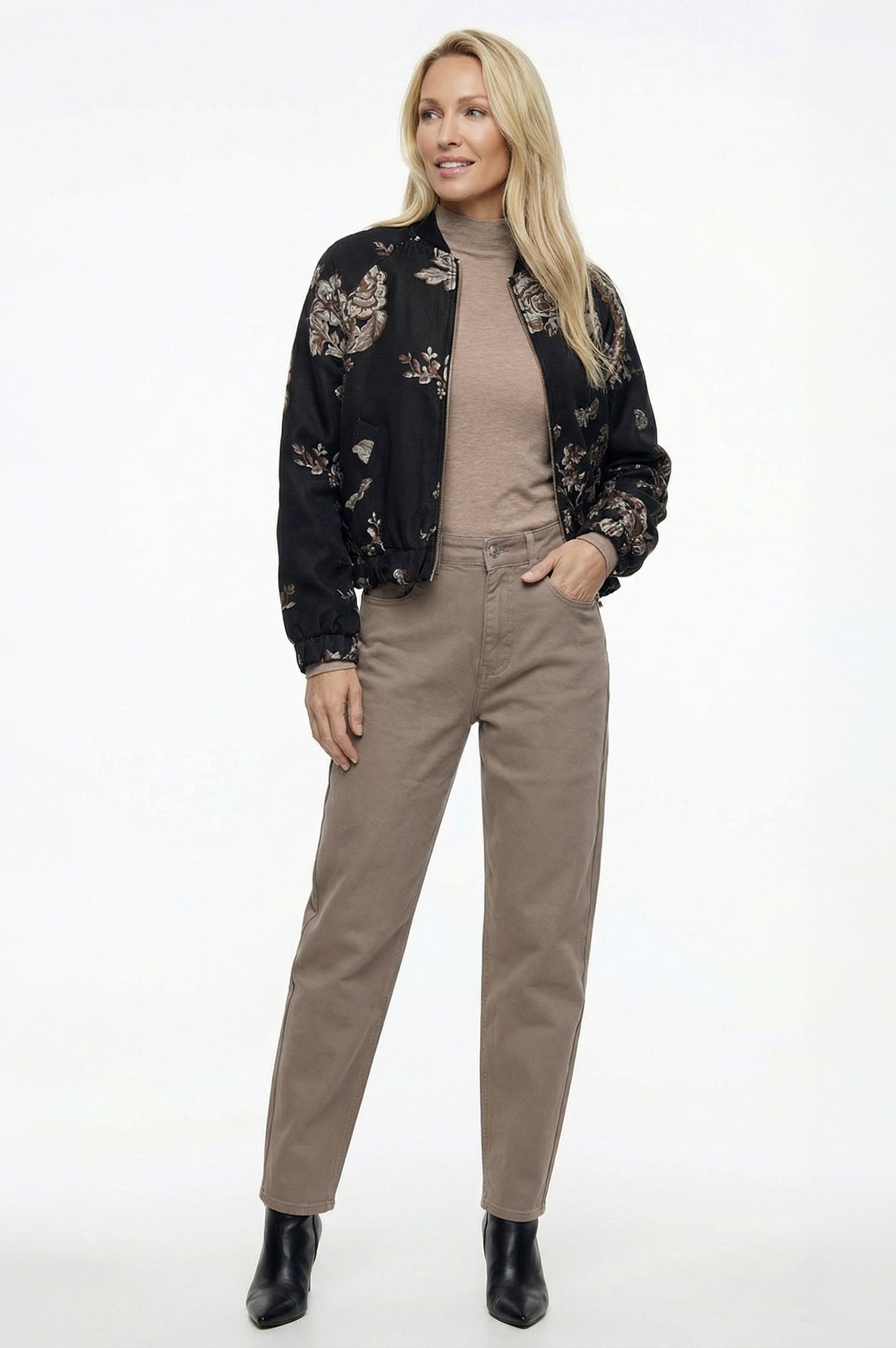 zandkleur barrel jeans gecombineerd met een beige coltrui en stoere bomberjack met bloemenmotief